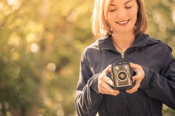 Cute girl is making pictures with a vintage camera, outside - Фото, зображення