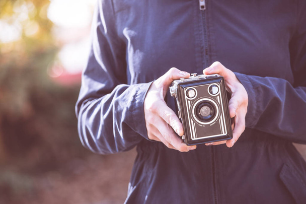 Girl is holding a vintage camera in her hands - Foto, Imagen