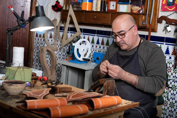 ремесленник, работающий с кожей в своей маленькой мастерской
 - Фото, изображение