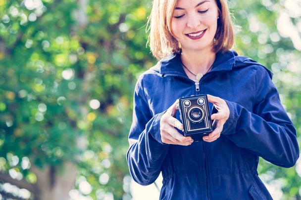 Cute girl is making pictures with a vintage camera, outside - Foto, imagen
