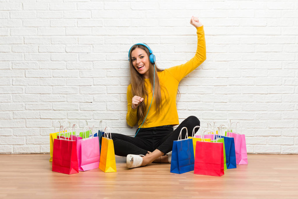 Młoda dziewczyna z dużo torby na zakupy słuchanie muzyki przez słuchawki i taniec - Zdjęcie, obraz