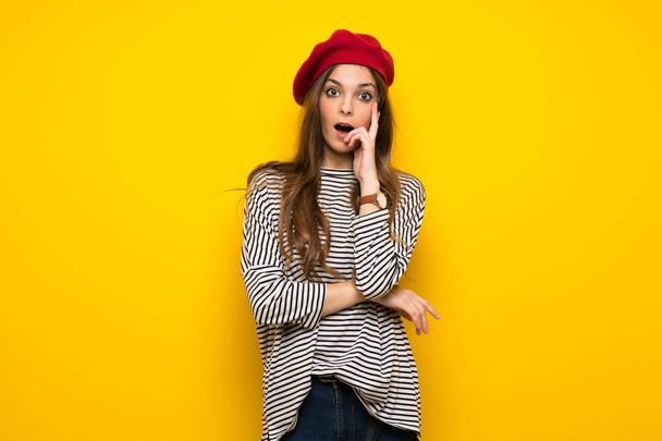 Meisje met Franse stijl over gele muur verrast en geschokt terwijl het juiste zoeken - Foto, afbeelding