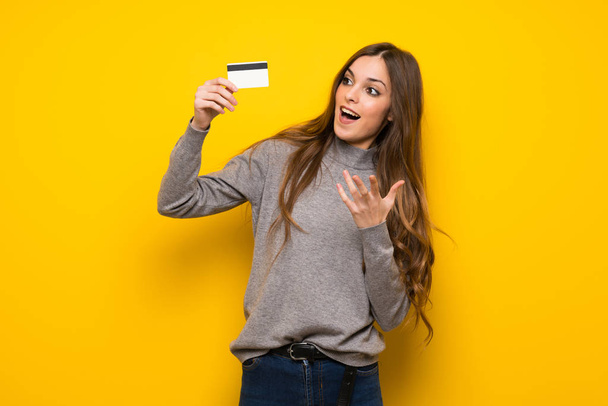 Mujer joven sobre pared amarilla sorprendida y enviando un mensaje
 - Foto, Imagen
