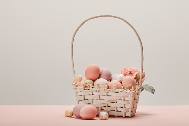 eater chicken and quail eggs in straw basket with flower on grey background  - Φωτογραφία, εικόνα