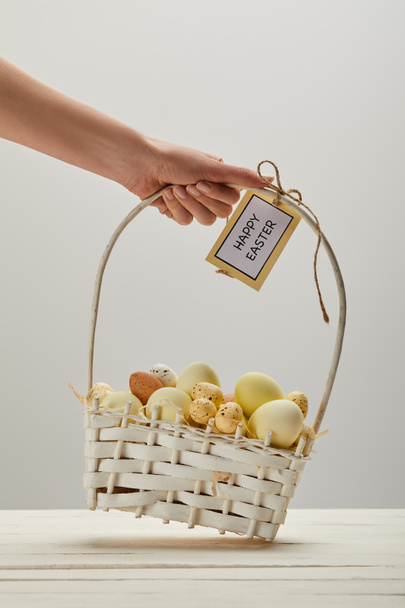 Vue recadrée d'une femme tenant un panier de paille avec du poulet de Pâques et des œufs de caille, carte avec un lettrage de Pâques heureux
 - Photo, image