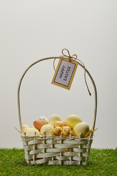 easter chicken and quail eggs in straw basket with flower and card with happy easter lettering on grass - 写真・画像