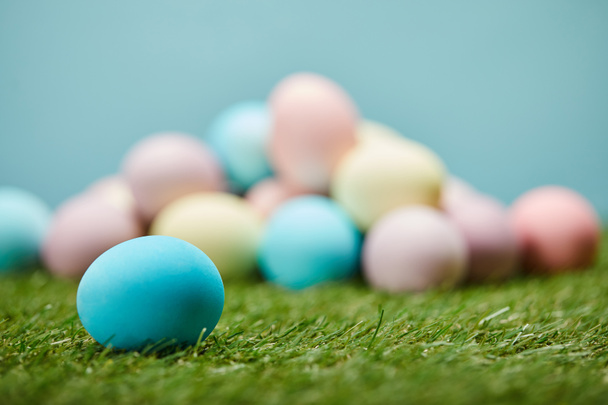 selective focus of easter eggs on grass on blue background  - Фото, изображение