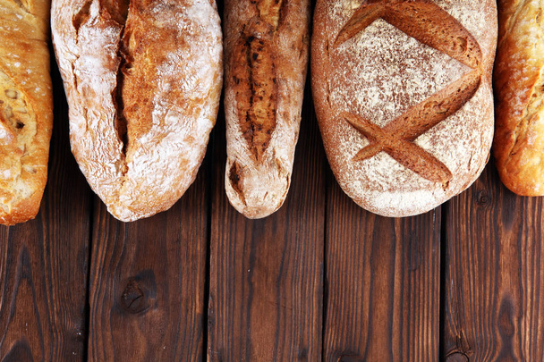 Sortimento de pão assado e pães em fundo de mesa de madeira. Conceito de cartaz de padaria
 - Foto, Imagem