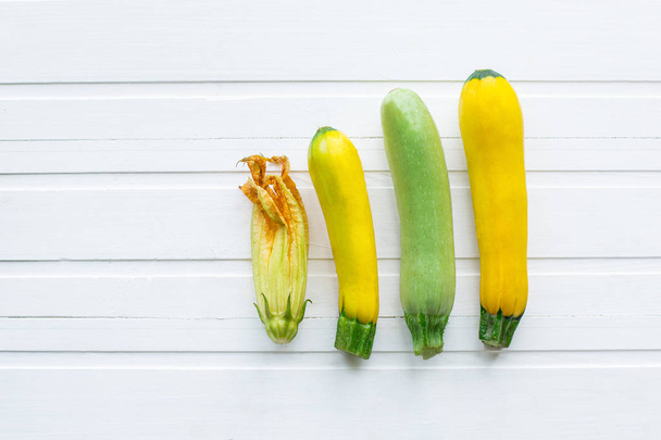 Green and yellow zucchini. Fresh vegetables. On a white wooden table. View from above. Copy space - Foto, immagini