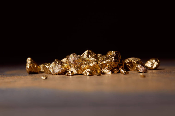 unbearbeitete goldene Steine auf Marmortisch isoliert auf schwarz - Foto, Bild