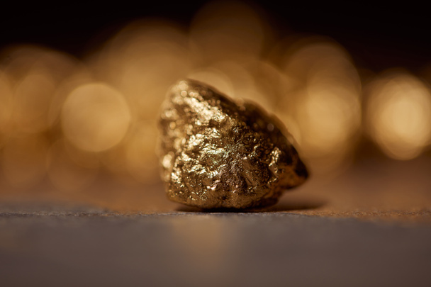 selective focus of golden stone on grey marble and blurred sparkling background - Foto, Imagem