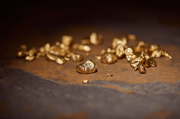 επιλεκτική εστίαση χρυσές πέτρες γκρι και μαρμάρινη επιφάνεια με θολή φόντο σκούρο - Φωτογραφία, εικόνα