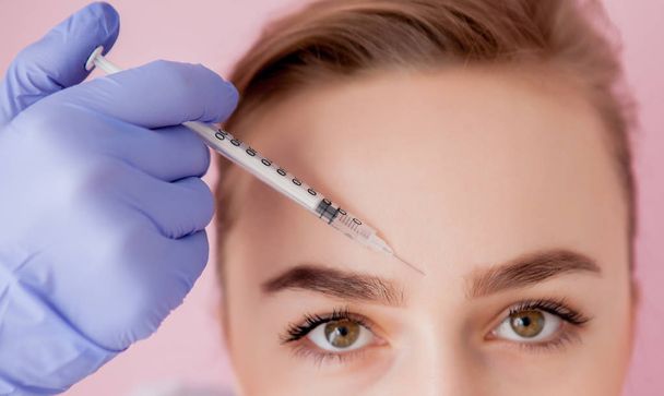 The doctor cosmetologist makes the Rejuvenating facial injections procedure for tightening and smoothing wrinkles on the face skin of a beautiful, young woman in a beauty salon.Cosmetology skin care. - Fotoğraf, Görsel