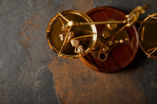 top view of golden stones on scales on grey and brown marble table - 写真・画像
