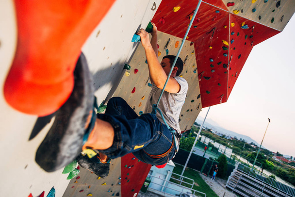 Homem alpinista na parede de escalada artificial em bouldering ginásio
 - Foto, Imagem