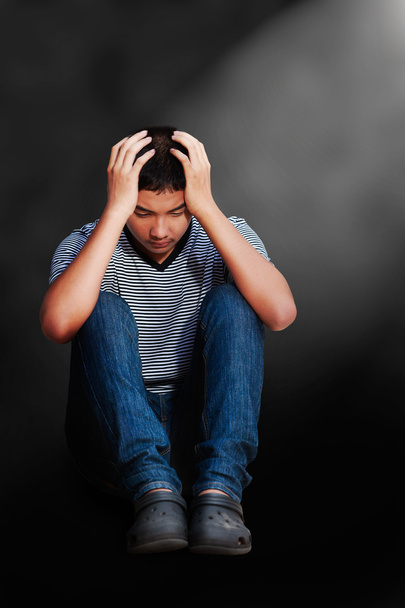 Triste asiático adolescente menino sentado no chão
 - Foto, Imagem
