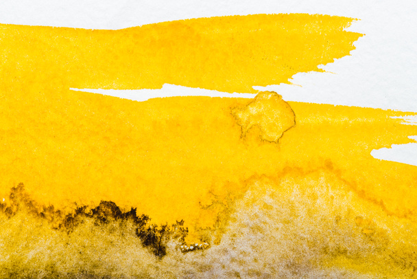 top view of yellow watercolor spill on white paper - 写真・画像