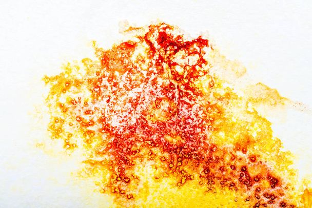 vista superior de los derrames de acuarela amarilla y roja sobre papel blanco
 - Foto, Imagen