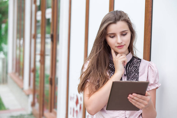 Açık havada duran tarama dijital tablet pad üzerinde çalışma çekici genç kadın öğrenci. Sarı uzun saçlı resmi gömlek bir tek kişiyle düşünceli hayalifener kız. Ofis Binası arka plan - Fotoğraf, Görsel