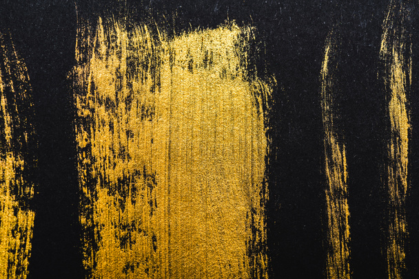 top view of yellow watercolor brushstrokes on black paper  - Фото, изображение