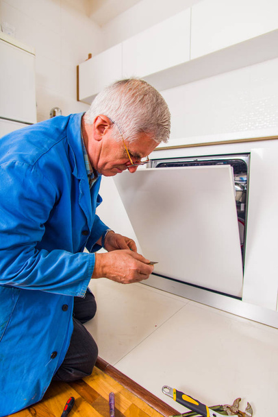 Handwerker öffnet die Spülmaschine in der Küche - Foto, Bild
