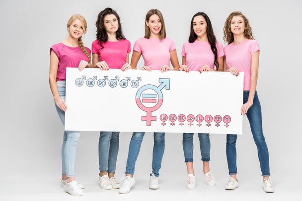 mujeres jóvenes atractivas sosteniendo un gran cartel con el símbolo de igualdad de género sobre fondo gris
 - Foto, imagen