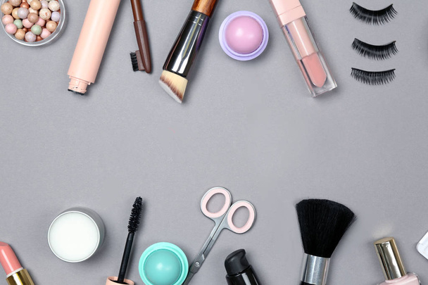 Набор косметики для макияжа с аксессуарами на сером фоне
 - Фото, изображение