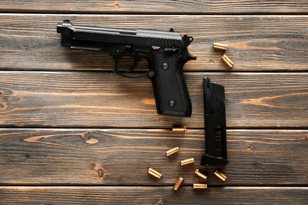 Pistolet, balles et chargeur sur fond bois - Photo, image