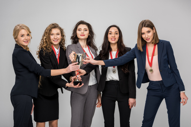 successful businesswomen holding trophy smiling isolated on grey  - Foto, Imagem