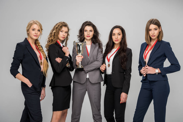 succesvolle vrouwelijke ondernemers houden trofee en permanent geïsoleerd op grijs  - Foto, afbeelding