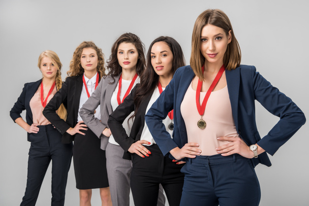 selective focus of successful businesswomen standing with medals isolated on grey  - Photo, Image