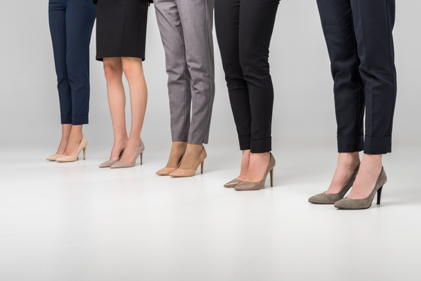 cropped view of women standing in hight heel shoes on grey background - Photo, Image