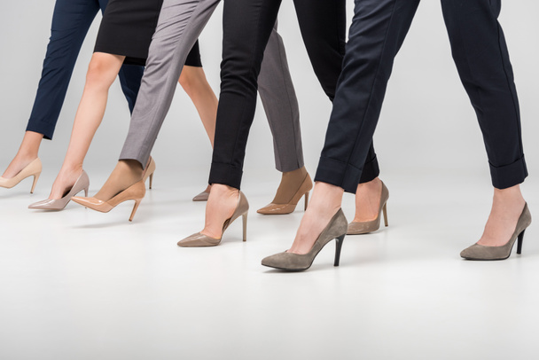 περικοπεί προβολή των γυναικών το περπάτημα στα υψηλά παπούτσια τακουνιών σε γκρίζο φόντο - Φωτογραφία, εικόνα
