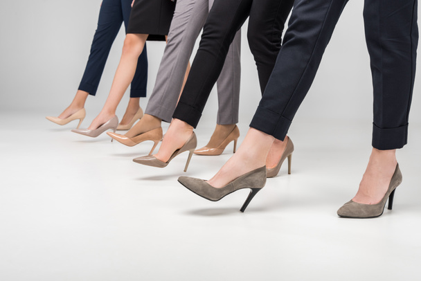 vista recortada de mujeres de negocios caminando en zapatos de tacón alto sobre fondo gris
 - Foto, imagen