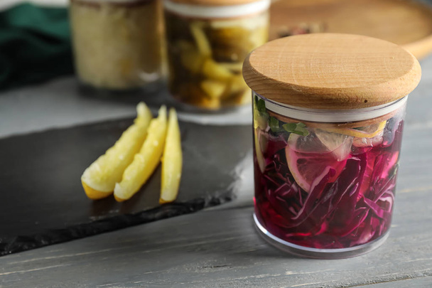 Glass jar with fermented cabbage and lemon on table - Photo, Image