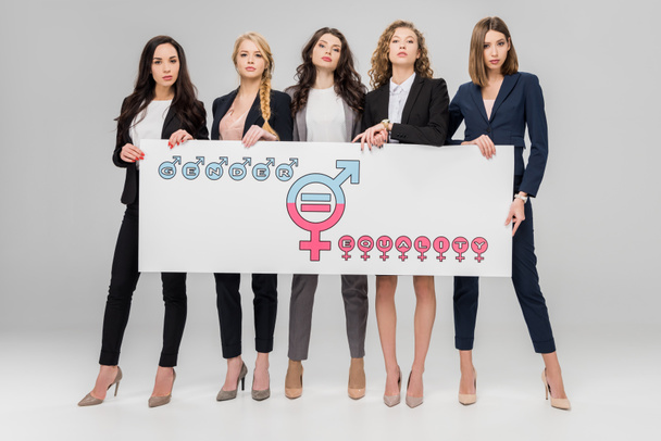 succesvolle jonge vrouwen houden van groot bord met gender gelijkheid symbool op grijze achtergrond - Foto, afbeelding