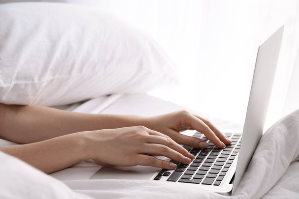Woman working on laptop in bed, closeup - Photo, Image