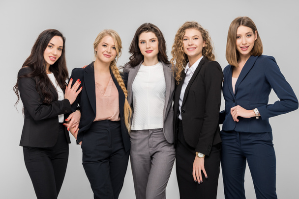 schöne junge Geschäftsfrauen, die isoliert auf grau stehen und lächeln - Foto, Bild