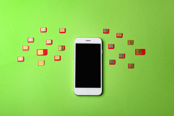 Mobiele telefoon en vele simkaarten op kleur achtergrond - Foto, afbeelding