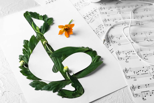 Скрипичный клюв из зеленых листьев и листов для заметок на столе
 - Фото, изображение