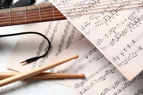 Komposition mit Gitarre, Drumsticks und Notenblättern auf weißem Hintergrund - Foto, Bild