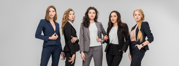 schöne erfolgreiche Frauen stehen mit Händen in Taschen isoliert auf grau  - Foto, Bild