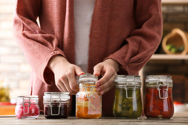 Woman with tasty fermented vegetables in jars on table - Photo, Image