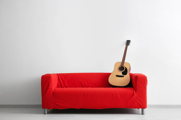Comfortable sofa with guitar near white wall - Foto, Imagen