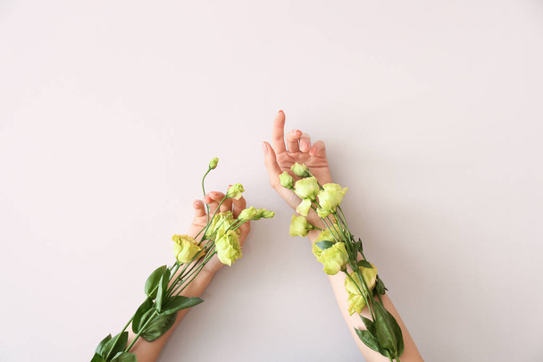 Γυναικεία χέρια με όμορφα λουλούδια στο φως φόντο - Φωτογραφία, εικόνα
