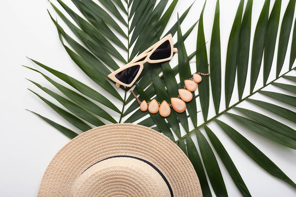 Sonnenbrille mit Hut, Halskette und Palmblättern auf weißem Hintergrund - Foto, Bild