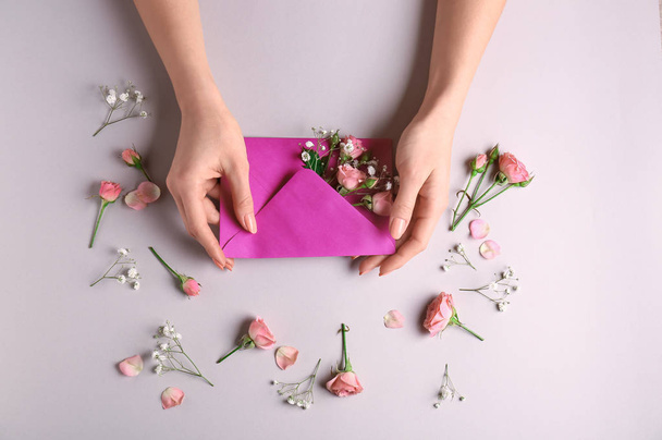 Mani femminili con busta di carta e bei fiori su sfondo chiaro
 - Foto, immagini