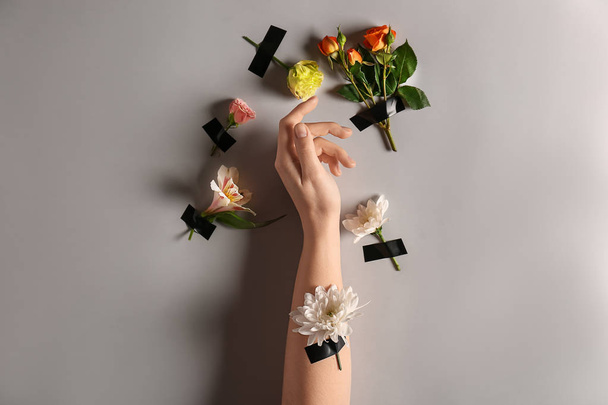 Female hand with beautiful flowers on light background - Foto, afbeelding