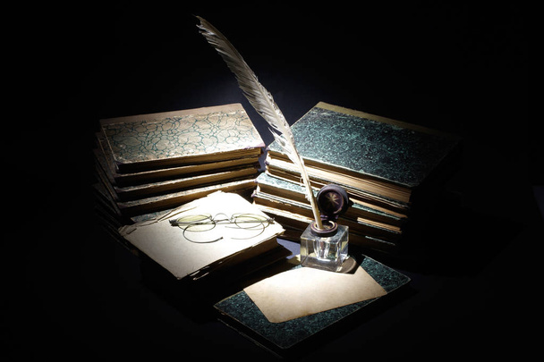 vintage concept - old books, papers, ink pen and inkpot on black background - Фото, изображение