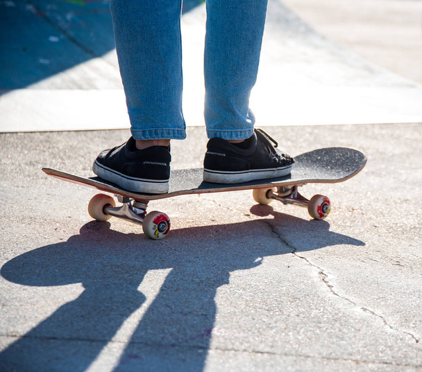  um patinador andando de skate em um parque de skate apenas a partir do joelho para baixo
 - Foto, Imagem